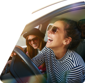 Dos chicas sonrientes disfrutan de su coche nuevo, compartiendo un momento de alegría.