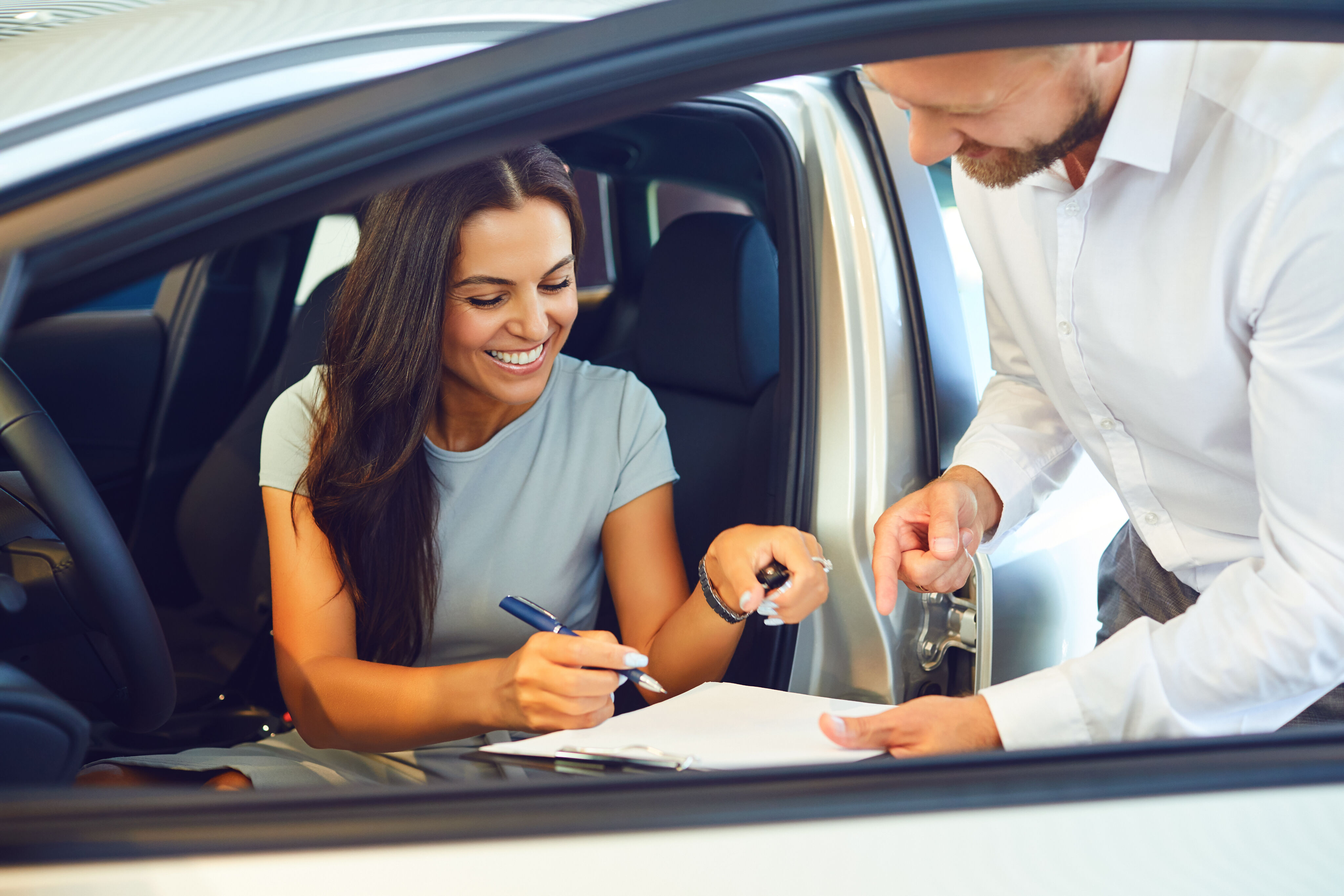 Imagen de un hombre y una mujer firmando un contrato en un coche