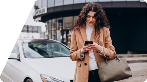 Mujer mira su teléfono móvil con un coche aparcado detrás