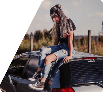 Una chica joven sentada en el techo de un coche al aire libre.