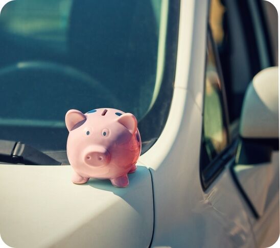 Imagen de una hucha con forma de cerdo encima de un coche